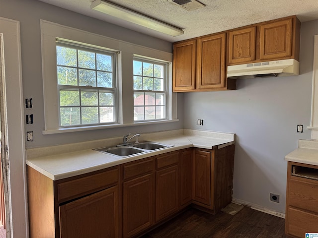 319 Lapsley Ave, Anniston, AL 36207 - kitchen featuring under cabinet range hood, brown cabinetry, dark wood-style flooring, light countertops, and a textured ceiling