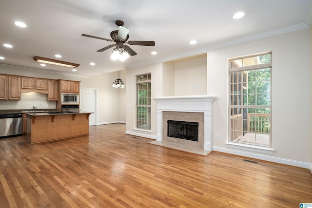 1819 Calgary Dr, Birmingham, AL 35022 - kitchen with appliances with stainless steel finishes, crown molding, a kitchen bar, light wood finished floors, and a fireplace