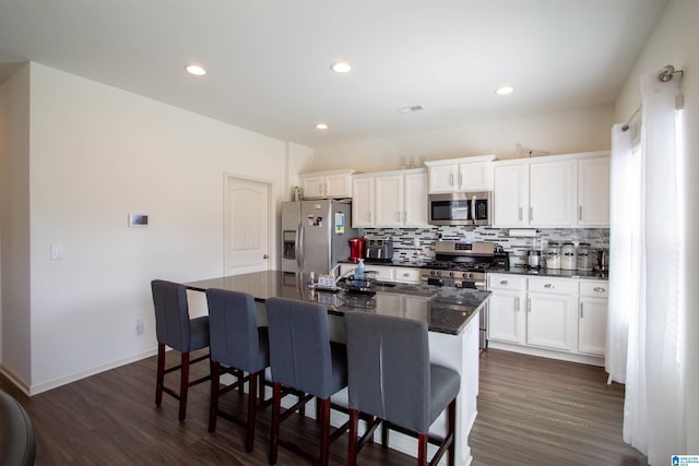 6497 Newbridge Dr, Bessemer, AL 35022 - kitchen featuring stainless steel appliances, a kitchen bar, a center island with sink, white cabinets, and backsplash