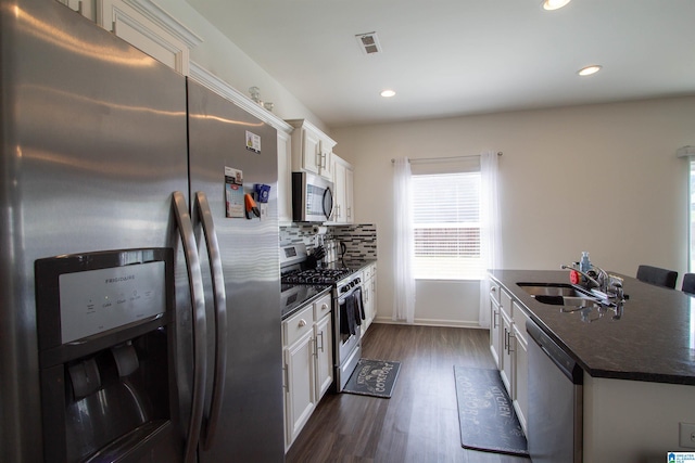 6497 Newbridge Dr, Bessemer, AL 35022 - kitchen with stainless steel appliances, dark countertops, white cabinetry, dark wood-style floors, and tasteful backsplash