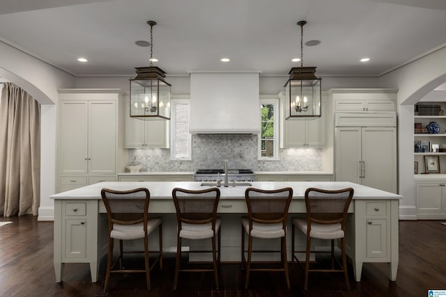 3600 Park Ln S, Mountain Brook, AL 35213 - kitchen with custom range hood, arched walkways, an island with sink, light countertops, and backsplash