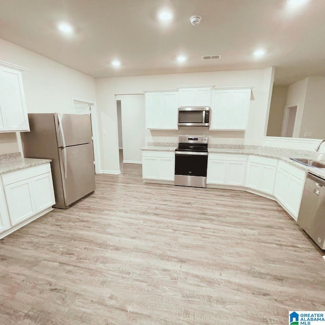 6936 Brandi Cir, Pinson, AL 35126 - kitchen with appliances with stainless steel finishes, light wood-style floors, white cabinetry, recessed lighting, and light stone countertops