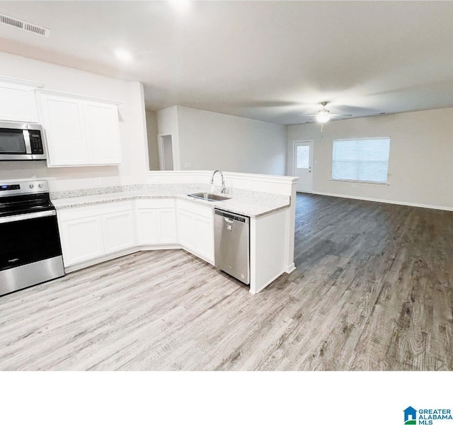 6936 Brandi Cir, Pinson, AL 35126 - kitchen featuring stainless steel appliances, a ceiling fan, a peninsula, light wood-style flooring, and white cabinets