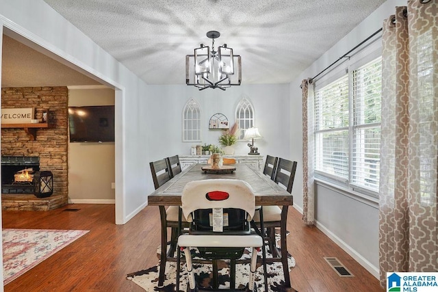 2089 Edenwood Cir, Hueytown, AL 35023 - dining space featuring a textured ceiling, wood finished floors, a chandelier, and a stone fireplace