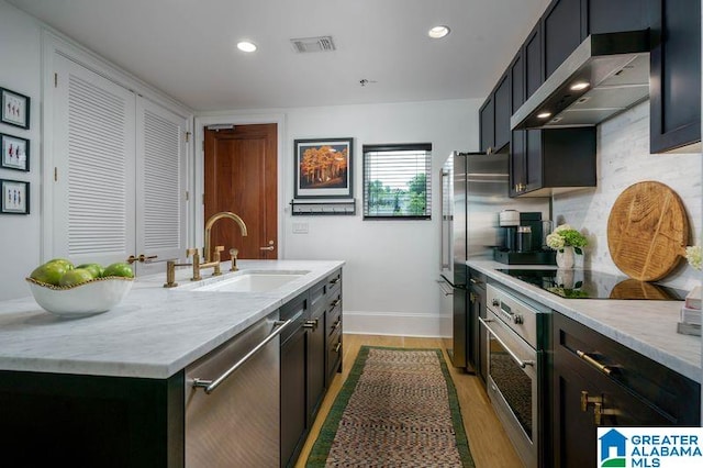 1300 27th Pl Unit 65, Birmingham, AL 35205 - kitchen with appliances with stainless steel finishes, ventilation hood, light wood-style flooring, an island with sink, and recessed lighting