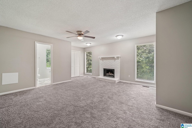 5919 Creekwood Rd, Irondale, AL 35210 - unfurnished living room with healthy amount of natural light, a ceiling fan, carpet, a brick fireplace, and a textured ceiling