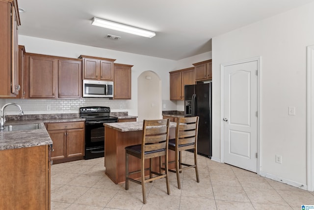 394 Glen Cross Way, Trussville, AL 35173 - kitchen with black appliances, arched walkways, a center island, backsplash, and light tile patterned floors