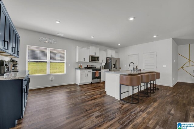 181 Halifax Ln, Chelsea, AL 35043 - kitchen featuring stainless steel appliances, dark wood-type flooring, a kitchen bar, light stone countertops, and an island with sink