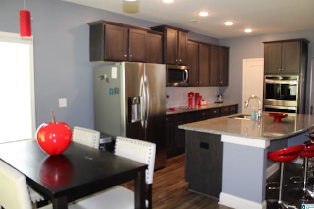 6284 Fieldbrook Cir, Mccalla, AL 35111 - kitchen with appliances with stainless steel finishes, dark wood finished floors, recessed lighting, a breakfast bar area, and a center island with sink