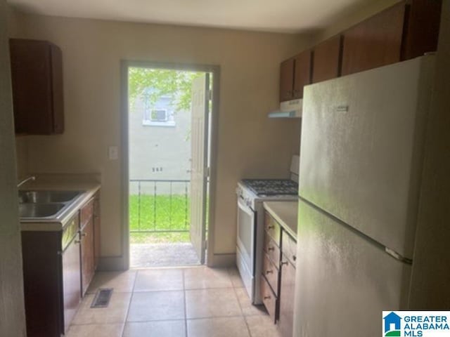 605 39th Pl, Fairfield, AL 35064 - kitchen with white appliances, ventilation hood, light countertops, light tile patterned flooring, and brown cabinetry