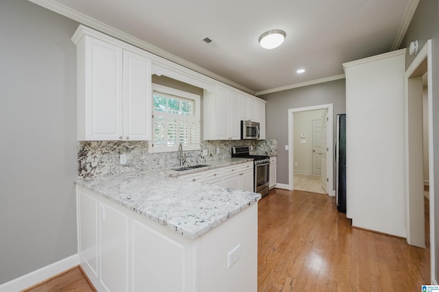 932 Cove Cir, Hoover, AL 35244 - kitchen with stainless steel appliances, ornamental molding, backsplash, a peninsula, and white cabinetry