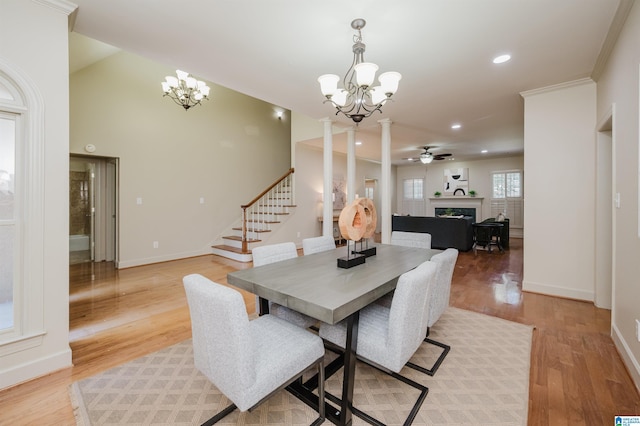 932 Cove Cir, Hoover, AL 35244 - dining area with a chandelier, light wood-style floors, a fireplace, stairs, and a ceiling fan