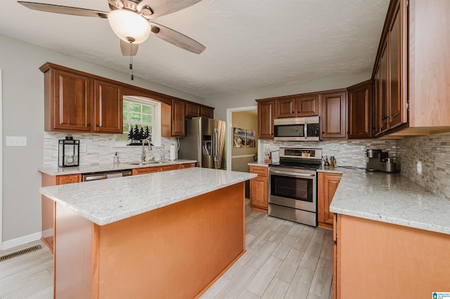 3350 Rosemary Ln, Vestavia Hills, AL 35216 - kitchen featuring appliances with stainless steel finishes, a ceiling fan, a kitchen island, tasteful backsplash, and light wood-style floors