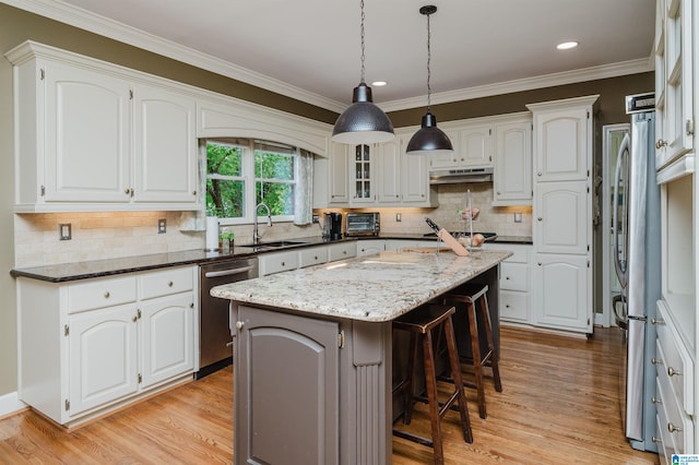 4208 Waterford Ln, Trussville, AL 35173 - kitchen featuring appliances with stainless steel finishes, light wood finished floors, a center island, white cabinetry, and a kitchen breakfast bar