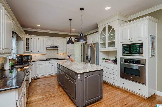 4208 Waterford Ln, Trussville, AL 35173 - kitchen featuring appliances with stainless steel finishes, white cabinetry, under cabinet range hood, light wood-style floors, and crown molding