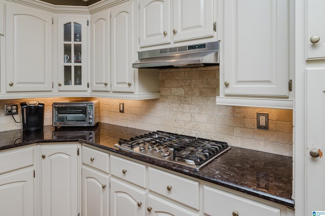 4208 Waterford Ln, Trussville, AL 35173 - kitchen with under cabinet range hood, stainless steel gas cooktop, tasteful backsplash, white cabinets, and glass insert cabinets