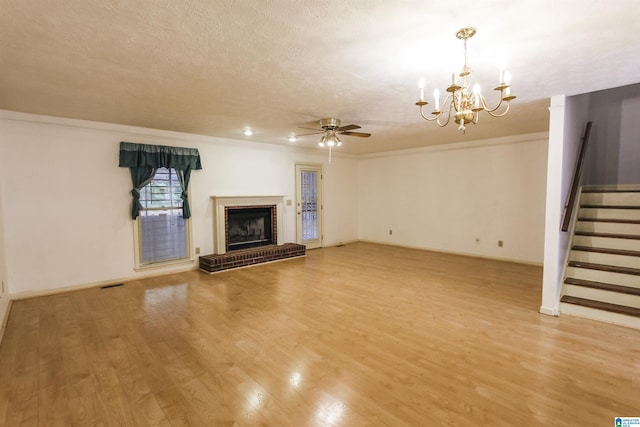 1534 Cambridge Pl, Anniston, AL 36207 - unfurnished living room featuring ceiling fan, stairway, a chandelier, light wood-style flooring, and a brick fireplace