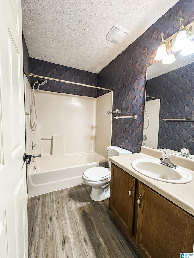 1534 Cambridge Pl, Anniston, AL 36207 - bathroom featuring wallpapered walls, wood finished floors, a textured ceiling, washtub / shower combination, and vanity