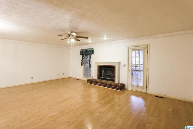 1534 Cambridge Pl, Anniston, AL 36207 - unfurnished living room with ceiling fan, light wood-type flooring, a fireplace, a textured ceiling, and ornamental molding