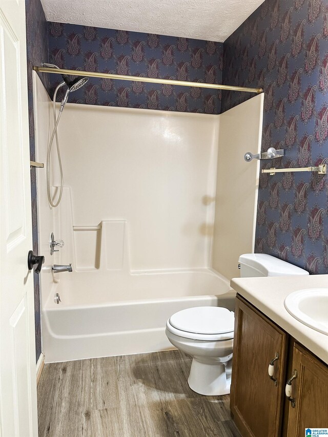 1534 Cambridge Pl, Anniston, AL 36207 - full bath featuring wallpapered walls, wood finished floors, vanity, tub / shower combination, and a textured ceiling