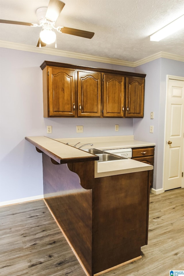 1534 Cambridge Pl, Anniston, AL 36207 - kitchen featuring a kitchen breakfast bar, light wood-type flooring, crown molding, light countertops, and a peninsula
