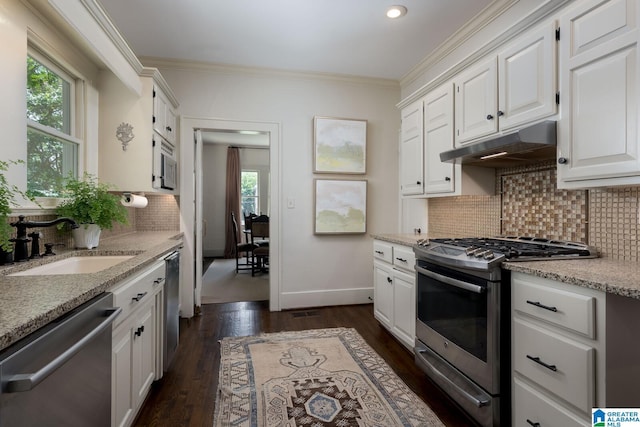 117 Elm St, Mountain Brook, AL 35213 - kitchen featuring stainless steel appliances, under cabinet range hood, white cabinetry, ornamental molding, and backsplash