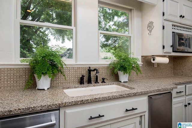 117 Elm St, Mountain Brook, AL 35213 - kitchen with stainless steel appliances, white cabinets, tasteful backsplash, and light stone countertops