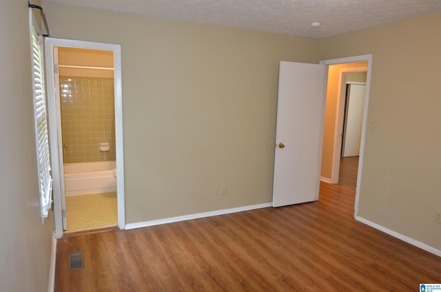 6301 Cedar Ct, Anniston, AL 36206 - unfurnished bedroom with wood finished floors, a textured ceiling, and connected bathroom