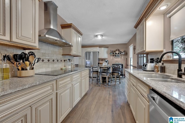 1025 Old Section Rd, Hoover, AL 35244 - kitchen featuring wall chimney range hood, appliances with stainless steel finishes, cream cabinets, and light wood-style flooring