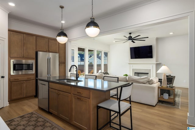 1313 Severn Way, Hoover, AL 35244 - kitchen featuring appliances with stainless steel finishes, a fireplace, light wood-style floors, ornamental molding, and an island with sink