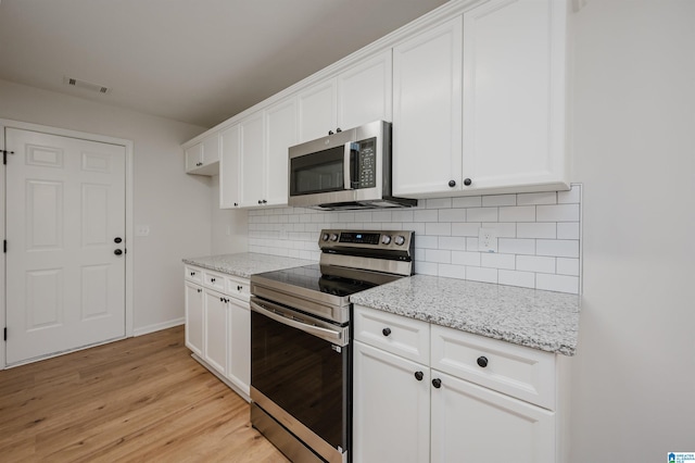 4022 Cambridge Dr, Moody, AL 35004 - kitchen with appliances with stainless steel finishes, light wood finished floors, tasteful backsplash, and white cabinetry