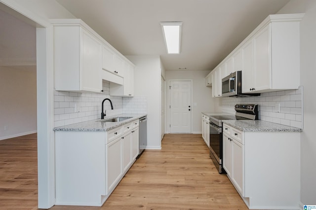 4022 Cambridge Dr, Moody, AL 35004 - kitchen with stainless steel appliances, decorative backsplash, light wood-type flooring, and white cabinetry