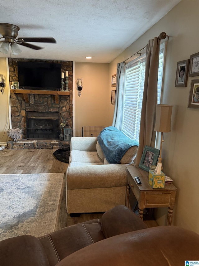 1500 Rockview Cir, Weaver, AL 36277 - living area with wood finished floors, a textured ceiling, a ceiling fan, a stone fireplace, and radiator