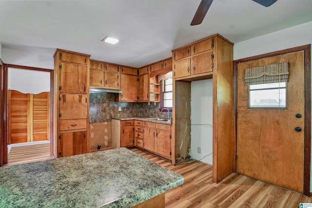 1257 Hueytown Rd, Hueytown, AL 35023 - kitchen featuring ceiling fan, light wood-style flooring, brown cabinets, decorative backsplash, and under cabinet range hood