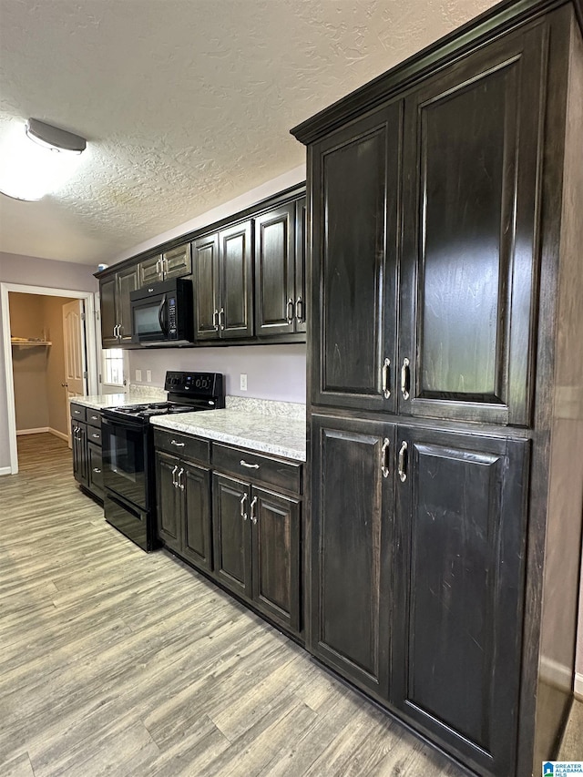 426 Bailey Rd, Weaver, AL 36277 - kitchen with black appliances, light wood finished floors, light countertops, a textured ceiling, and dark cabinetry