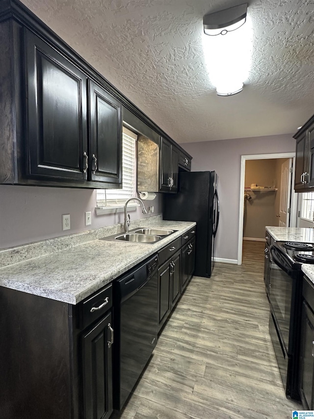 426 Bailey Rd, Weaver, AL 36277 - kitchen with black appliances, light countertops, light wood-type flooring, a textured ceiling, and dark cabinetry