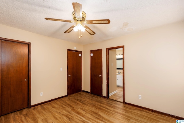 2517 Wright Cir, Birmingham, AL 35235 - unfurnished bedroom featuring light wood-style floors, multiple closets, ensuite bathroom, a textured ceiling, and ceiling fan