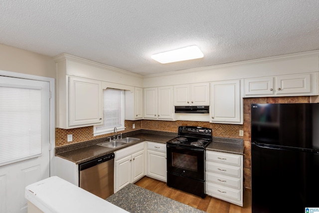 2517 Wright Cir, Birmingham, AL 35235 - kitchen with black appliances, under cabinet range hood, dark countertops, wood finished floors, and white cabinetry