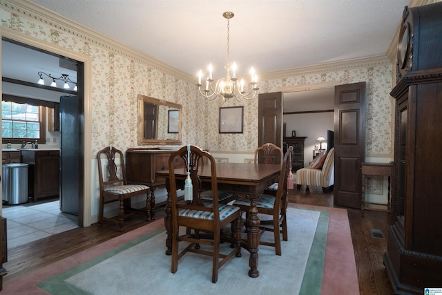 3518 William And Mary Rd, Hoover, AL 35216 - dining space featuring wallpapered walls, crown molding, a chandelier, light wood finished floors, and a wainscoted wall
