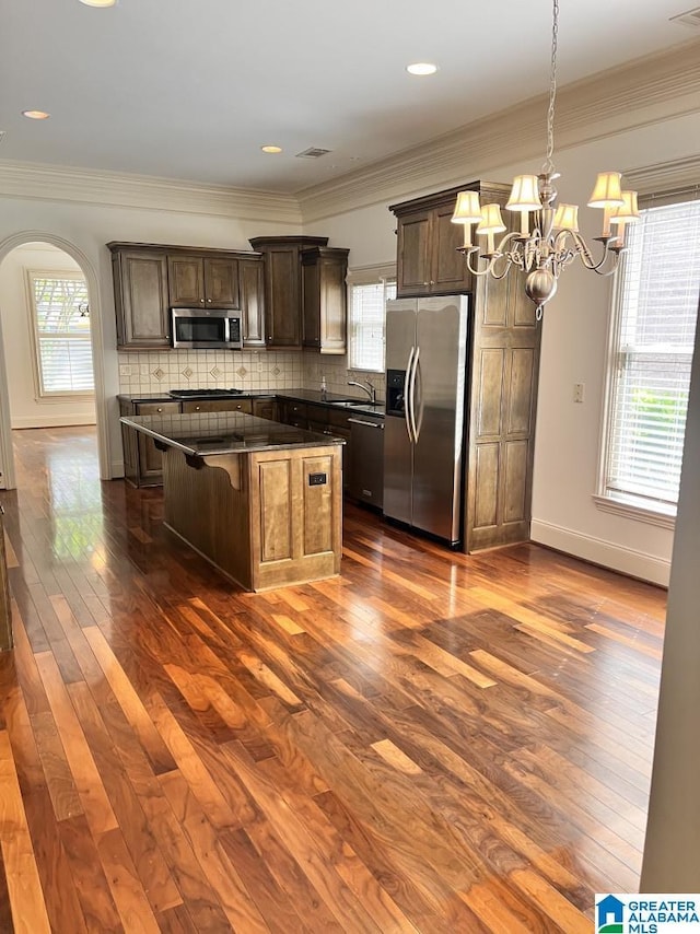 1664 Warren Ln, Vestavia Hills, AL 35243 - kitchen with appliances with stainless steel finishes, arched walkways, dark wood-style flooring, a chandelier, and a center island