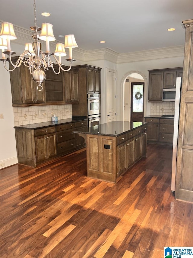 1664 Warren Ln, Vestavia Hills, AL 35243 - kitchen with appliances with stainless steel finishes, arched walkways, a chandelier, dark wood-style floors, and tasteful backsplash