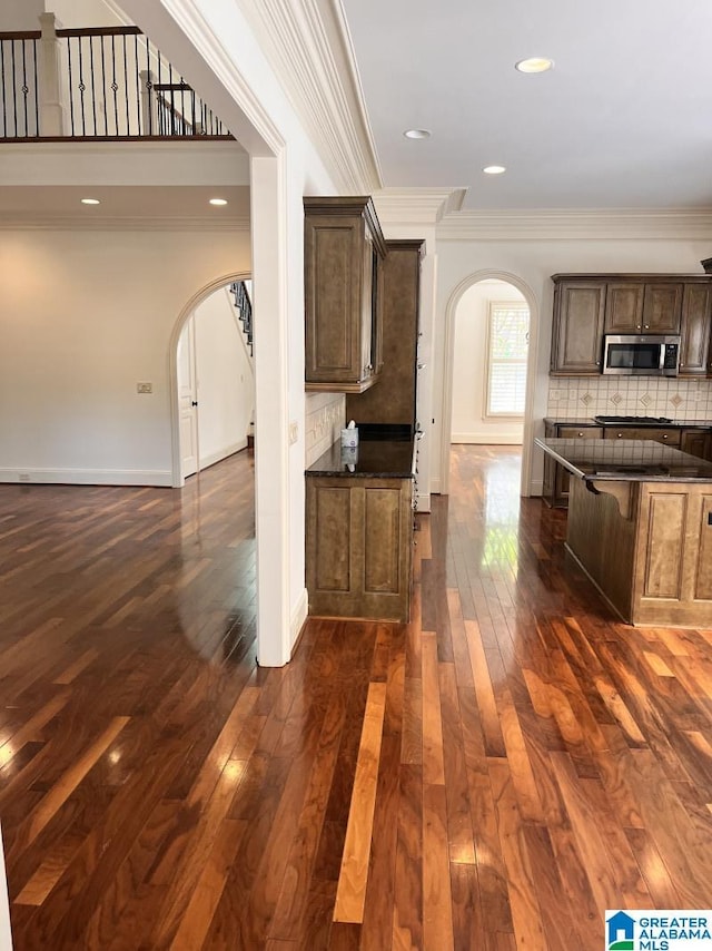 1664 Warren Ln, Vestavia Hills, AL 35243 - kitchen featuring arched walkways, stainless steel microwave, ornamental molding, dark wood finished floors, and tasteful backsplash