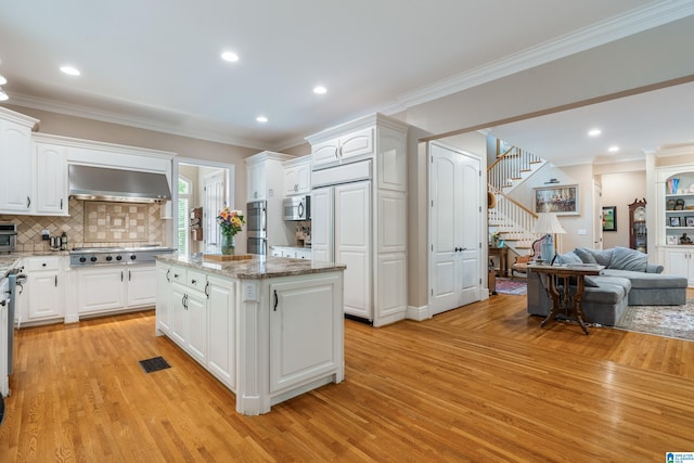 1007 Eagle Hill Dr, Birmingham, AL 35242 - kitchen featuring exhaust hood, light wood-style flooring, appliances with stainless steel finishes, open floor plan, and crown molding
