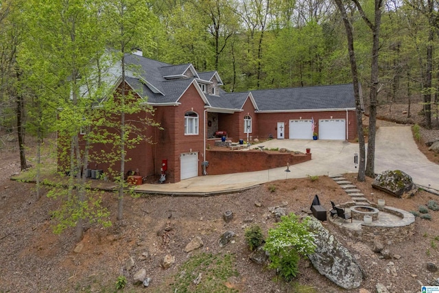 1007 Eagle Hill Dr, Birmingham, AL 35242 - view of front of house with an outdoor fire pit, concrete driveway, roof with shingles, a view of trees, and a chimney