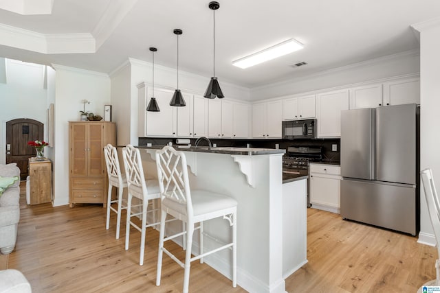 1185 Overlook Dr, Trussville, AL 35173 - kitchen featuring appliances with stainless steel finishes, a kitchen breakfast bar, dark countertops, light wood-style floors, and a peninsula