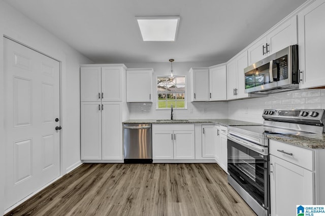 8312 Country Cir, Pinson, AL 35126 - kitchen with stainless steel appliances, light wood-style floors, white cabinetry, and backsplash