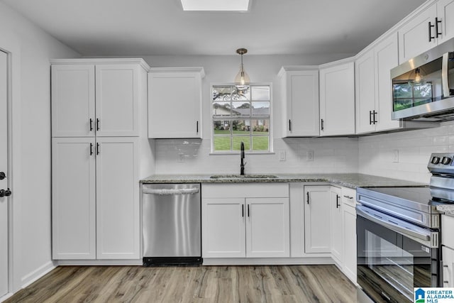 8312 Country Cir, Pinson, AL 35126 - kitchen with appliances with stainless steel finishes, light wood finished floors, white cabinets, light stone countertops, and tasteful backsplash