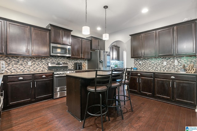 5432 Parkside Cir, Hoover, AL 35244 - kitchen featuring appliances with stainless steel finishes, arched walkways, dark brown cabinets, a kitchen bar, and tasteful backsplash