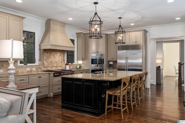 6902 Honor Keith Rd, Trussville, AL 35173 - kitchen with stainless steel appliances, custom range hood, cream cabinets, tasteful backsplash, and a kitchen island with sink