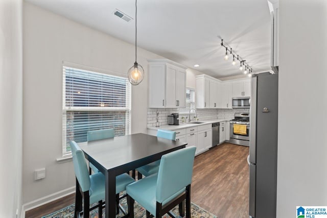 5633 Park Side Rd, Hoover, AL 35244 - kitchen featuring appliances with stainless steel finishes, backsplash, white cabinets, dark wood-style flooring, and decorative light fixtures